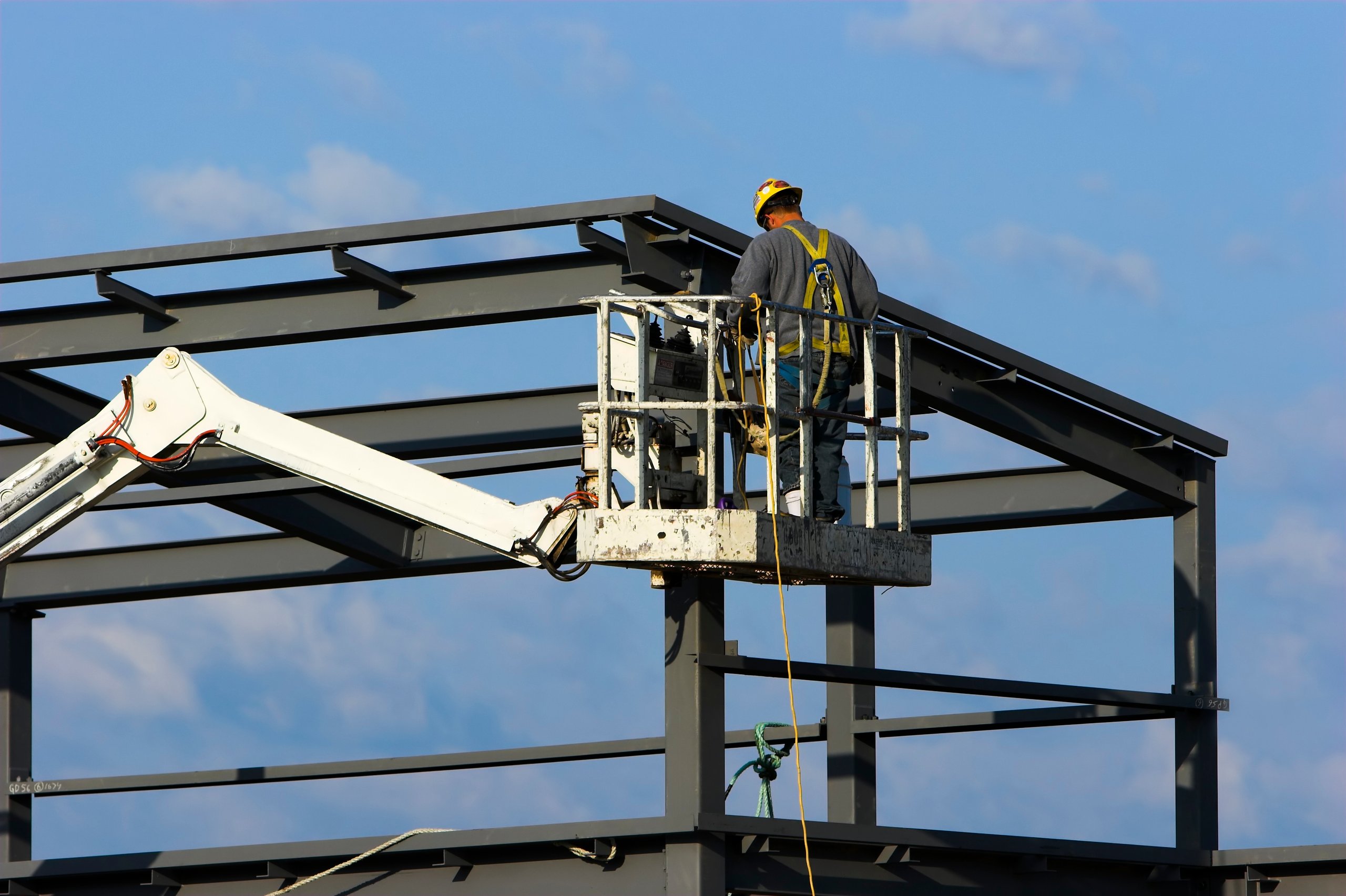 Construction worker on cherry picker at commercial building construction site