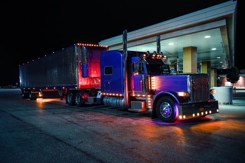 Classic semi truck with chrome reefer trailer at pump at night